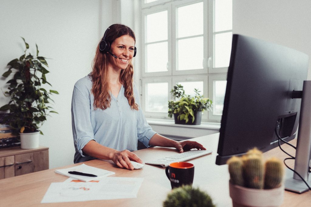 Frau mit Headset steht vor Computer